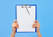 Clipboard in female hands on blue background Clipboard in female hands on blue background