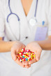 Photo: Pills, tablets and drugs heap in doctor's hand on blue backgroun Pills, tablets and drugs heap in doctor's hand on blue backgroun