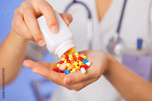 Photo: Pills, tablets and drugs pouring from bottle in doctor's hand on Pills, tablets and drugs pouring from bottle in doctor's hand on