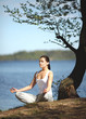 beautiful young girl training yoga near a lake under a tree beautiful young girl training yoga near a lake under a tree