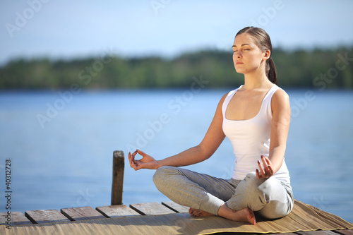 Photo: beautiful young girl training yoga near a lake beautiful young girl training yoga near a lake