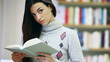 smiling female student with book in hands in a bookstore