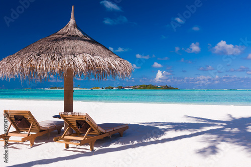 Photo: Chairs and umbrella on a beach with shadow from palm tree Chairs and umbrella on a beach with shadow from palm tree