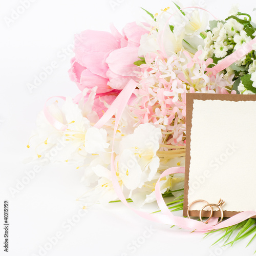 Gold wedding rings on a bouquet of white flowers with banner add