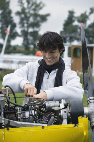Photo: Young man screwing in airplane engine Young man screwing in airplane engine