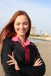 Redhead woman standing with hands folded , at the beach