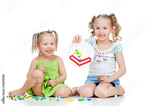 Photo: cute girls sisters playing together over white background cute girls sisters playing together over white background