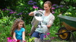 Mother watering flowers while her daughter is watching