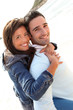 Man giving piggyback ride to girlfriend on the beach