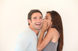 Beautiful woman whispering to boyfriend's ear
