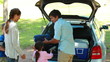 Father emptying the trunk of the car with his family