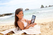 Beautiful woman in bikini using tablet on the beach