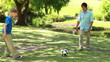 Smiling man playing soccer with his son