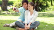 Couple sitting on the grass while photographing themselves