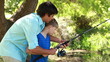 Father and son using a fishing rod together