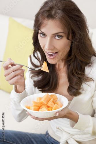 Photo: Brunette Woman Eating Melon At Home on Sofa Brunette Woman Eating Melon At Home on Sofa