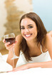 Woman with glass of red wine, on bed Woman with glass of red wine, on bed