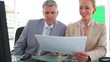 Two colleagues discussing information on a document