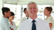 Video: Smiling director posing with his employees in background Smiling director posing with his employees in background