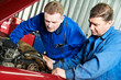 two car mechanic diagnosing auto engine problem