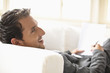 Businessman lying on sofa, holding document and pen, smiling