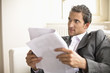 Businessman sitting on sofa, holding document