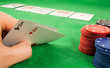 A pair of aces in a hand with chips and cards in the background