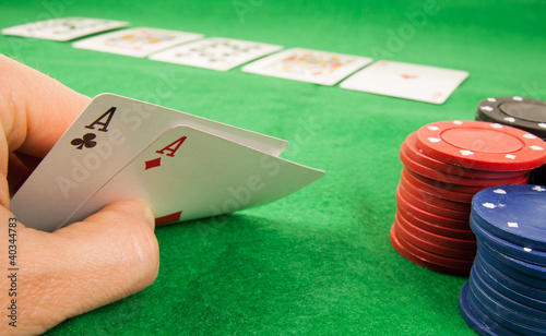 Фото: A pair of aces in a hand with chips and cards in the background A pair of aces in a hand with chips and cards in the background