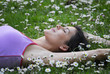 Joven mujer recostada sobre flores en primavera.