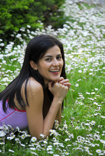 Photo: Joven mujer recostada sobre flores en primavera. Joven mujer recostada sobre flores en primavera.