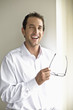 Photo: Mid adult man holding glasses, portrait Mid adult man holding glasses, portrait