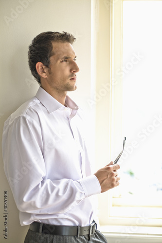 Photo: Mid adult man holding glasses, contemplating Mid adult man holding glasses, contemplating