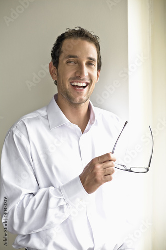 Photo: Mid adult man holding glasses, portrait Mid adult man holding glasses, portrait