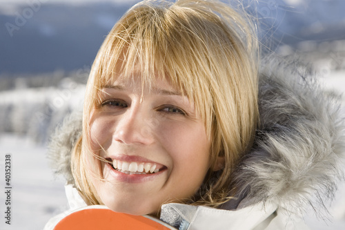 Photo: Young woman holding snowboard, smiling, portrait Young woman holding snowboard, smiling, portrait
