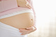 Pregnant woman with hand on belly, close-up