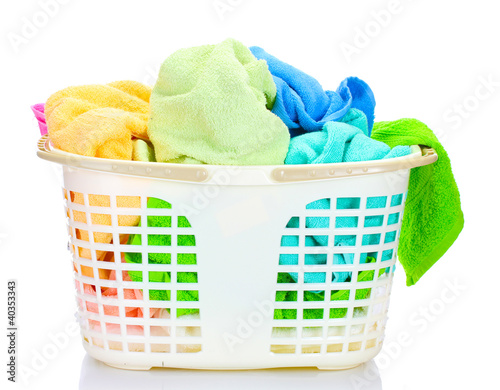 Photo: Plastic basket with bright towels isolated on white Plastic basket with bright towels isolated on white