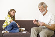 Girl playing cards with grandfather, smiling