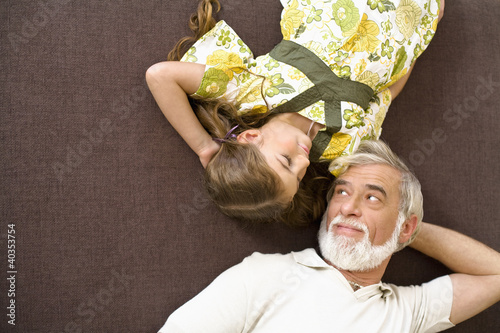 Photo: Senior man and girl resting on sofa Senior man and girl resting on sofa