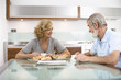 Foto: Senior couple having breakfast at dinning table, smiling Senior couple having breakfast at dinning table, smiling
