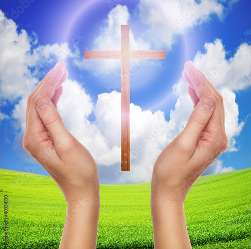 Photo: hands praying with cross in sky - easter concept hands praying with cross in sky - easter concept