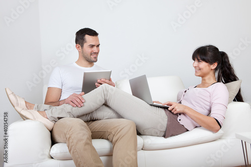 Photo: Young couple using laptops in couch Young couple using laptops in couch