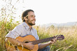 Mid adult man playing guitar in field