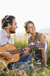 Mid adult couple in field with guitar