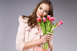 young brunette woman in pink coat holding flowers