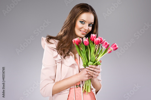Photo: young brunette woman in pink coat holding flowers young brunette woman in pink coat holding flowers