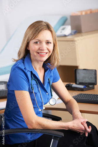Photo: Portrait UK doctor sitting at desk Portrait UK doctor sitting at desk