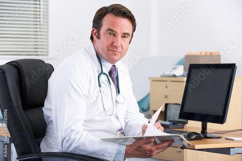 Photo: Portrait UK doctor sitting at desk Portrait UK doctor sitting at desk