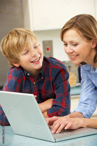 Photo: Mother and son using laptop in domestic kitchen Mother and son using laptop in domestic kitchen