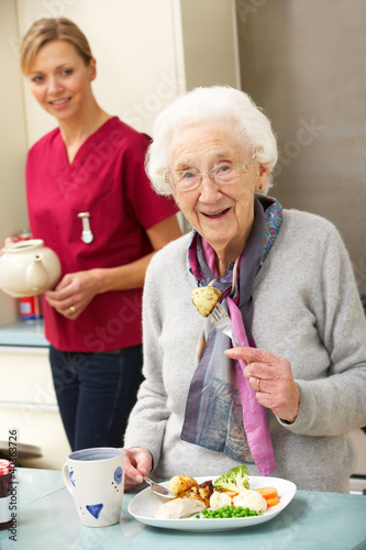 Photo: Senior woman with carer eating meal at home Senior woman with carer eating meal at home
