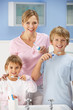 Mother and children cleaning teeth in bathroom